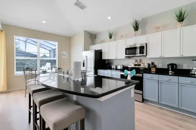 a kitchen with white cabinets and a large island with chairs at Four Bed Pool/Spa Home-Windsor Palms Resort in Kissimmee