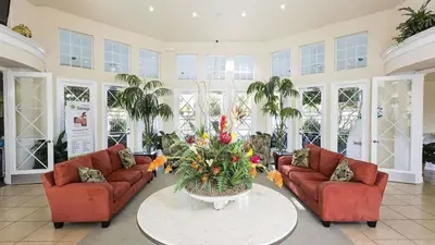 a living room with two couches and a table with flowers at Four Bed Pool/Spa Home-Windsor Palms Resort in Kissimmee