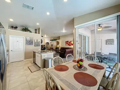 a kitchen and dining room with a table and chairs at Tranquility Palms in a Resort- Steps to Disney in Kissimmee