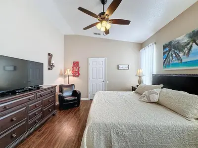 a bedroom with a bed and a flat screen tv at Tranquility Palms in a Resort- Steps to Disney in Kissimmee