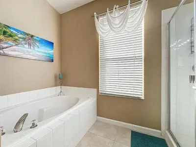 a bathroom with a bath tub and a window at Tranquility Palms in a Resort- Steps to Disney in Kissimmee
