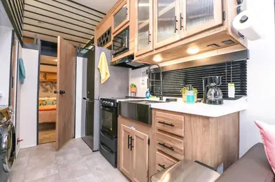 a kitchen with wooden cabinets and a black appliance at FunTropicalTinyHomeGolfCartLake in Orlando