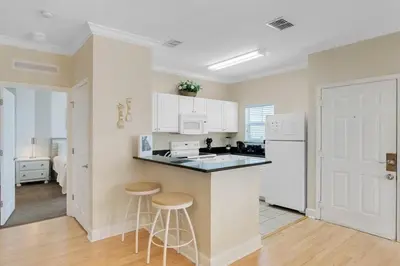 a kitchen with white appliances and two stools in it at Casa 4Q + Sala de Jogos – 15 min da Disney in Kissimmee