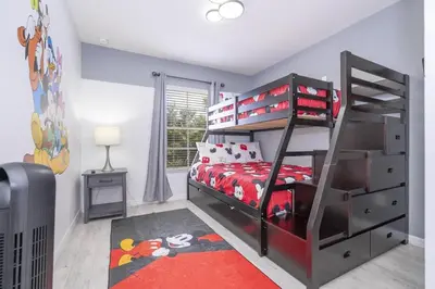 a bedroom with a bunk bed with a red bedspread at Beautiful Townhouse In Bella Vida Resort in Kissimmee
