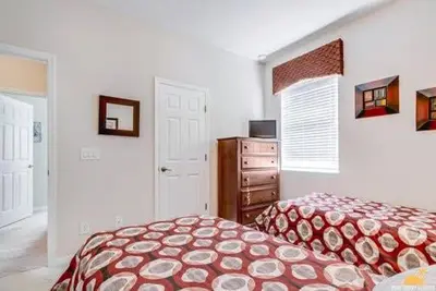 a bedroom with a bed and a dresser at BellaVida Palms Private Screened Pool Home in Kissimmee