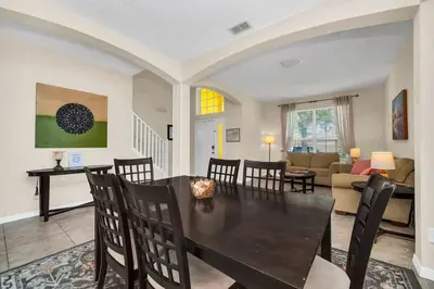 a dining room and living room with a table and chairs at Remodeled 7 Bedroom Retreat Near Disney World in Kissimmee
