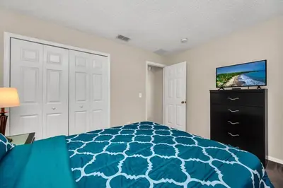a bedroom with a bed and a tv on a wall at Remodeled 7 Bedroom Retreat Near Disney World in Kissimmee