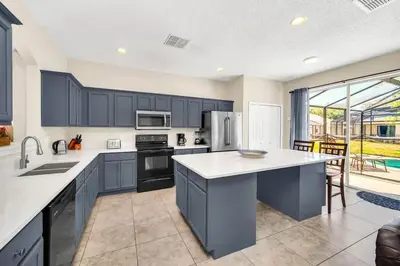 a kitchen with blue cabinets and a large kitchen island at Remodeled 7 Bedroom Retreat Near Disney World in Kissimmee
