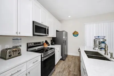 a kitchen with white cabinets and a stainless steel refrigerator at Colorful Villa Near Disney With Margaritaville Resort & Island H20 Waterpark Access - 3197Cs in Orlando