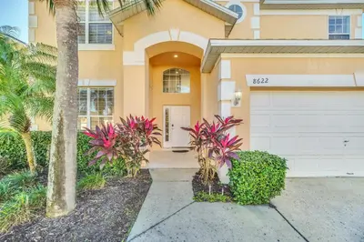 a house with a garage and a palm tree at Emerald Island Resort 6 bedroom 4 bathroom luxury in Kissimmee