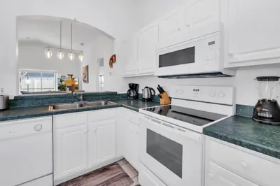 a white kitchen with white cabinets and green counter tops at Cute Vacation Home Very Close to Disney in Orlando