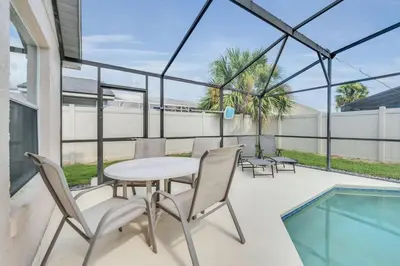 a patio with a table and chairs and a pool at Cute Vacation Home Very Close to Disney in Orlando