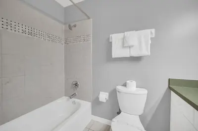 a white bathroom with a toilet and a bath tub at Lindfields Reserve with Private Pool in Kissimmee