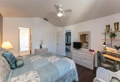 a bedroom with a bed with a ceiling fan and a desk at Beautiful Pool Home by Disney World in Orlando