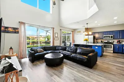 a living room with a black leather couch and a kitchen at Wonderful Terra Verde Orlando Vacation Home in Kissimmee