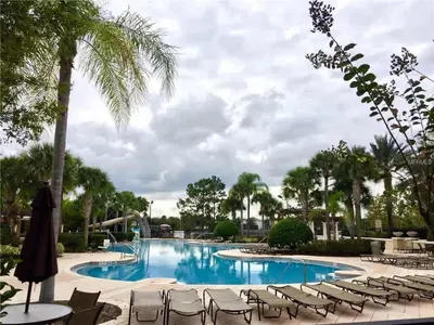 a swimming pool with chairs and a palm tree at 3 Bedrooms Condo Only Minutes From Disney in Orlando