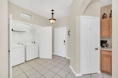 a kitchen with white cabinets and a white tile floor at 3 Bedrooms Condo Only Minutes From Disney in Orlando