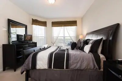 a bedroom with a large bed with a dresser and windows at Windsor Hills Resort Pool Villa Near Disney in Orlando