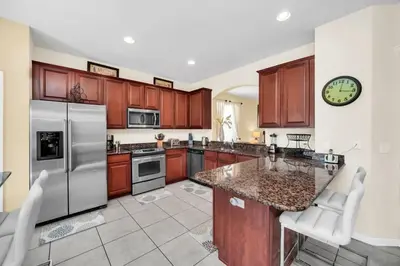 a kitchen with wooden cabinets and stainless steel appliances at Windsor Hills Dream Private Screened Pool Home in Orlando