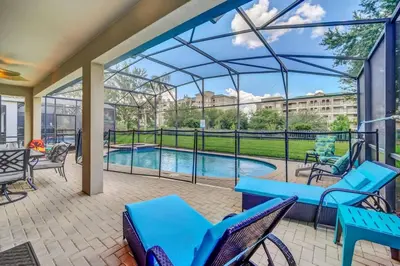 a patio with blue chairs and a swimming pool at Windsor Hills Dream Private Screened Pool Home in Orlando