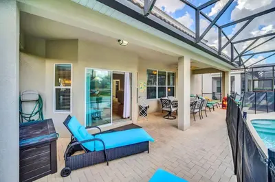 a patio with a swimming pool and a blue couch and chairs at Windsor Hills Dream Private Screened Pool Home in Orlando