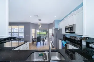 a kitchen with white cabinets and a black counter top at Luxury 6 Bedroom Pool Home in Windsor Hills in Orlando