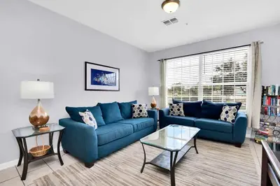a living room with two blue couches and a table at Beautiful Vacation Condo at Windsor Palms Resort in Kissimmee