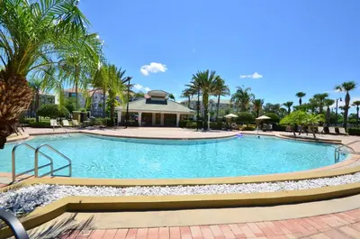 a large swimming pool with palm trees and a building at Cozy 3BR Apartment - Vista Cay Resort near Disney! in Orlando