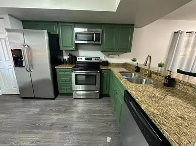 a kitchen with green cabinets and a stainless steel refrigerator at Central Hub in Orlando