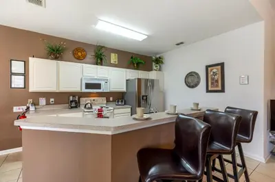 a kitchen with a bar with leather bar chairs at Olivia's Dream Villa on WindsorHills in Orlando
