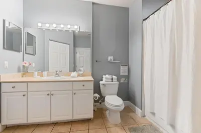 a bathroom with a toilet and a sink and a mirror at Casa 4Q Lucaya com Temas Disney e Clubhouse in Kissimmee