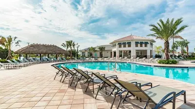 a pool at a resort with chairs and a building at Magic Moments in Kissimmee