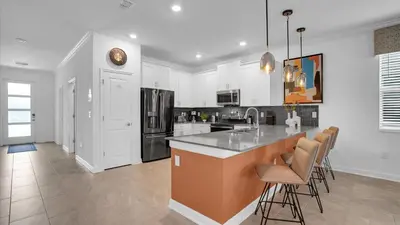 a kitchen with white cabinets and a island with bar stools at Sierra Sky in Kissimmee