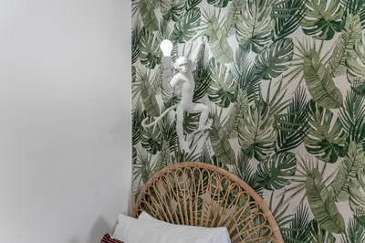 a room with a chair and a wall with a tropical wallpaper at 5BD - Movie Room, Pool, BBQ - Near Disney World in Kissimmee