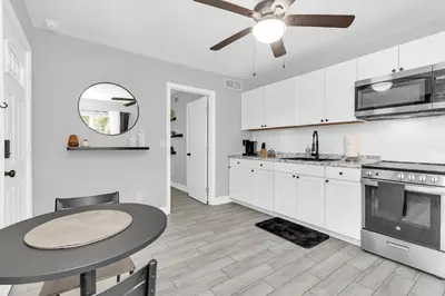 a white kitchen with a table and a ceiling fan at Modern Cuartito near Winter Park in Orlando