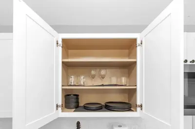 a kitchen cabinet with plates and glasses in it at Modern Cuartito near Winter Park in Orlando