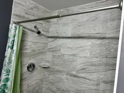 a shower in a bathroom with a stone wall at Tranquile Vacation Home near Universal studio in Orlando