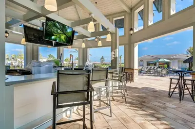 a patio with chairs and a bar with a flat screen tv at Storey Lake Resort 2bd Condo Overlooking Water #840 condo in Kissimmee