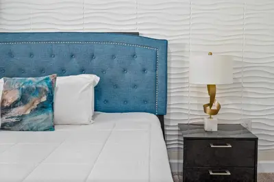 a bed with a blue headboard and a table with a lamp at 9 min to Disney w Pool ARCADE FREE Waterpark Villa in Kissimmee