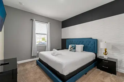 a bedroom with a blue bed and a window at 9 min to Disney w Pool ARCADE FREE Waterpark Villa in Kissimmee