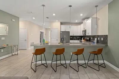 a kitchen with three bar stools and a counter at 9 min to Disney w Pool ARCADE FREE Waterpark Villa in Kissimmee