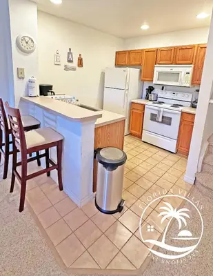a kitchen with a white refrigerator and a table at Villas Standard Seven Dwrafs Resort - Close to Disney in Kissimmee