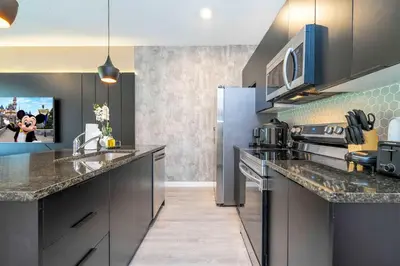 a kitchen with stainless steel appliances and a tv at 3221 Brand New Family 3BD Townhouse near Disney in Kissimmee