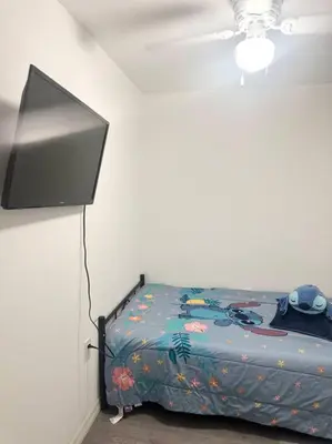 a bedroom with a bed with a tv on the wall at The Pink House of Celebration in Kissimmee