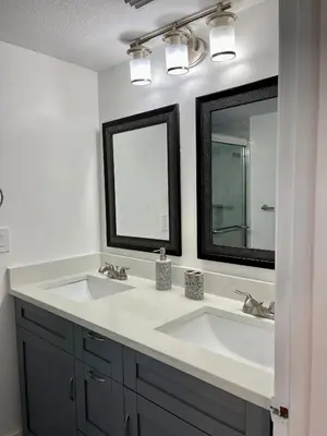a bathroom with two sinks and two mirrors at Luxury Getaway 3BR Apartment near Disney Parks in Kissimmee