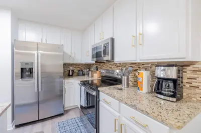 a kitchen with white cabinets and stainless steel appliances at Family 4br House w Pool near to Disney Much More in Kissimmee