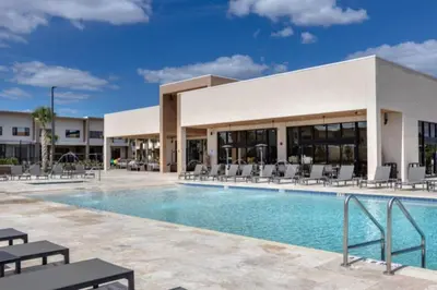 a pool at a resort with chairs and a building at 3 Bedroom 4 Bathroom Magic Village 3099 in Orlando