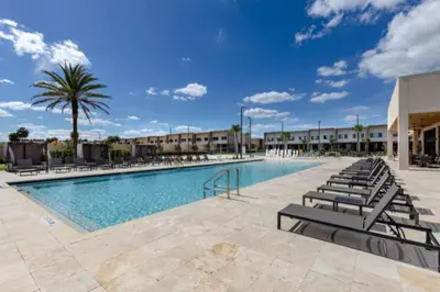 a swimming pool with lounge chairs and a palm tree at 3 Bedroom 4 Bathroom Magic Village 3099 in Orlando
