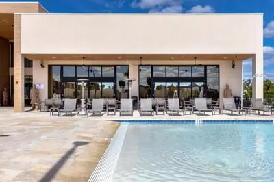 a swimming pool with chairs and a building at 3 Bedroom 4 Bathroom Magic Village 3099 in Orlando