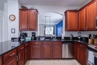 a large kitchen with wooden cabinets and appliances at Magical 6BR Family Retreat with Pool Near Disney in Orlando
